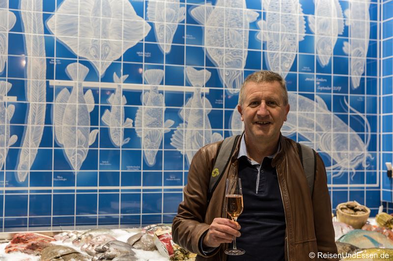 Mit Champagner vor der Fischtheke mit handbemalten Fließen im Frischeparadies München