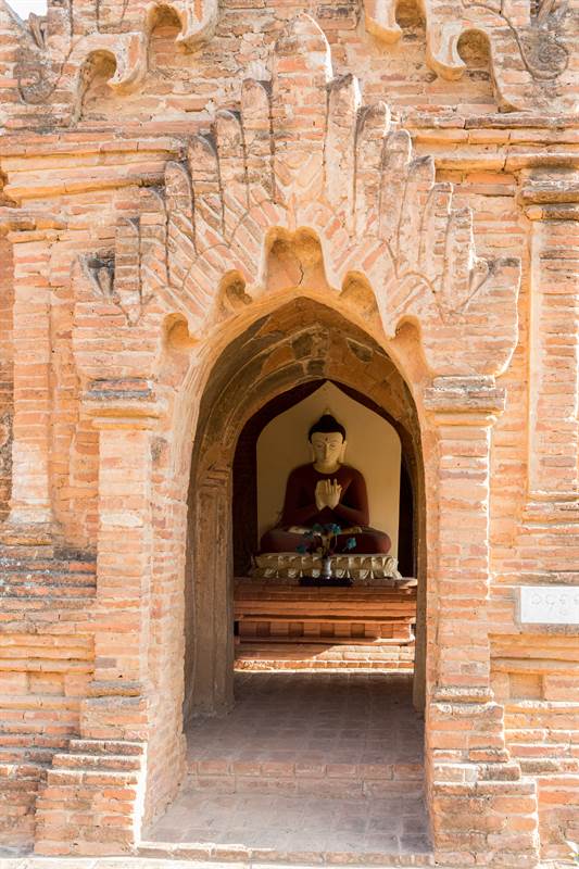Buddhafigur mit Opfergaben bei einer Pagode in Old Bagan