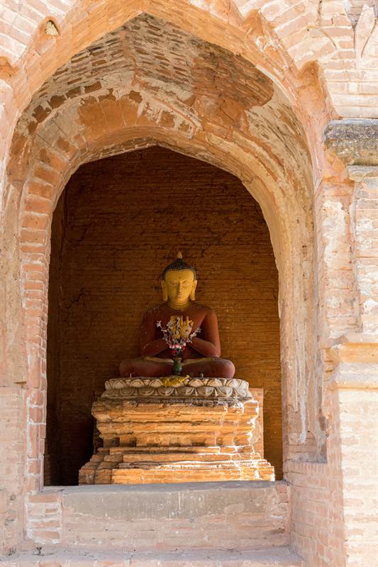 Buddhafigur mit Opfergaben bei einer Pagode in Old Bagan