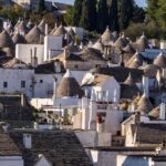 Alberobello Trulli: Der ultimative Reiseguide für Apuliens Märchenstadt Am Hang vom Rione Monti stehen unzähligeTrulli-Häuser aus Stein mit kegelförmigen grauen Dächern. Die Häuser reihen sich dicht an dicht. Die Trulli in Alberobello sind eine fantastische Attraktion.