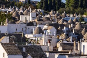 Am Hang vom Rione Monti stehen unzähligeTrulli-Häuser aus Stein mit kegelförmigen grauen Dächern. Die Häuser reihen sich dicht an dicht. Die Trulli in Alberobello sind eine fantastische Attraktion.